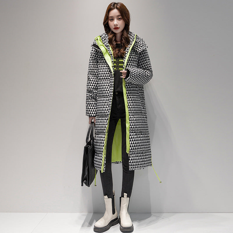 Woman wearing a long, patterned coat with a geometric design on a gray background