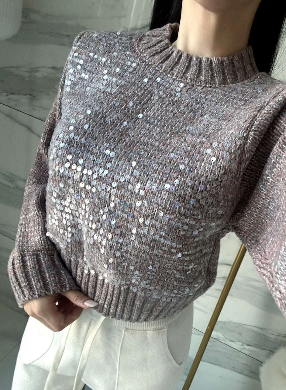 Close-up of a person wearing a sparkly sweater with a blurred background