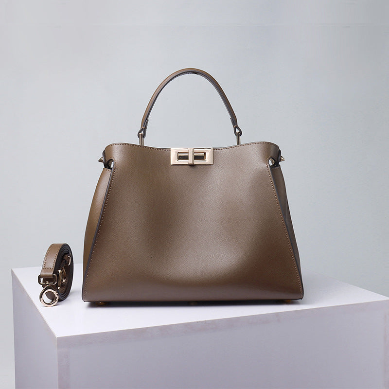 Taupe crossbody handbag with metal clasp, top handles, and side strap