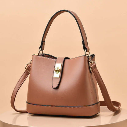 Blush pink tote handbag with short handles, shoulder strap, and gold clasp hardware