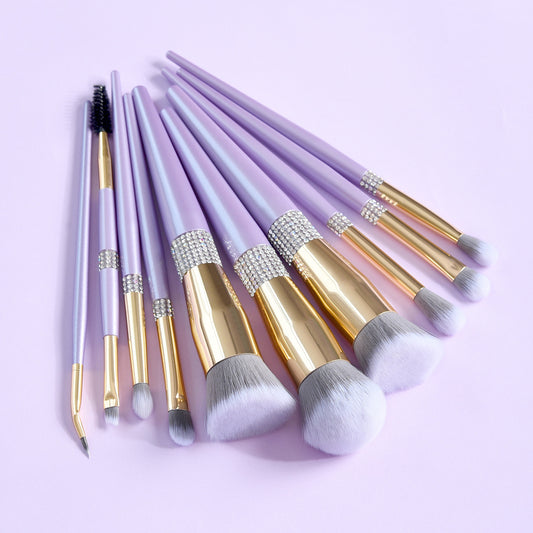 Set of makeup brushes with purple handles and gold accents on a light purple background