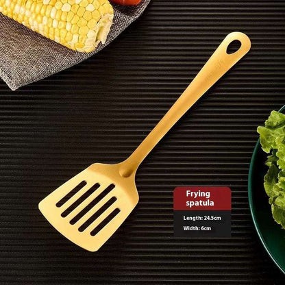 Gold frying spatula on a black surface with corn and lettuce.