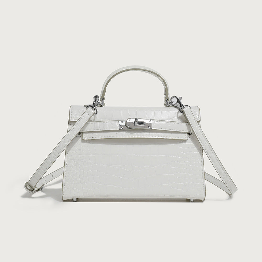 White mini handbag with croc-textured finish, top handle, flap front, and clasp