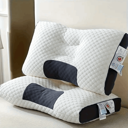 White ergonomic massage pillows with dark support inserts, stacked on a bed