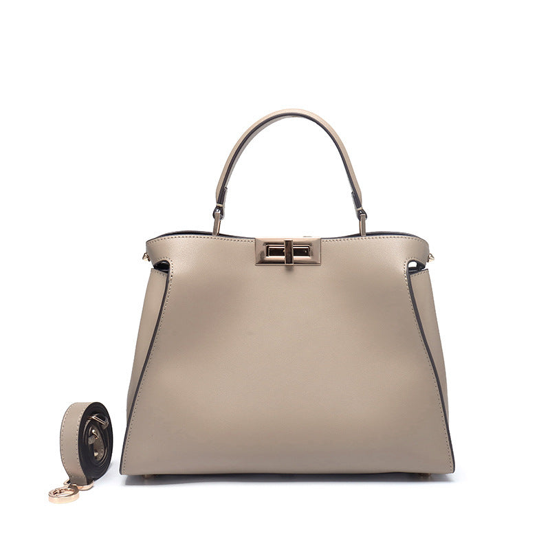 Beige crossbody handbag, front view with gold-tone lock clasp and side strap tabs