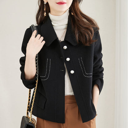 Woman wearing a black coat with white buttons, holding a black handbag.