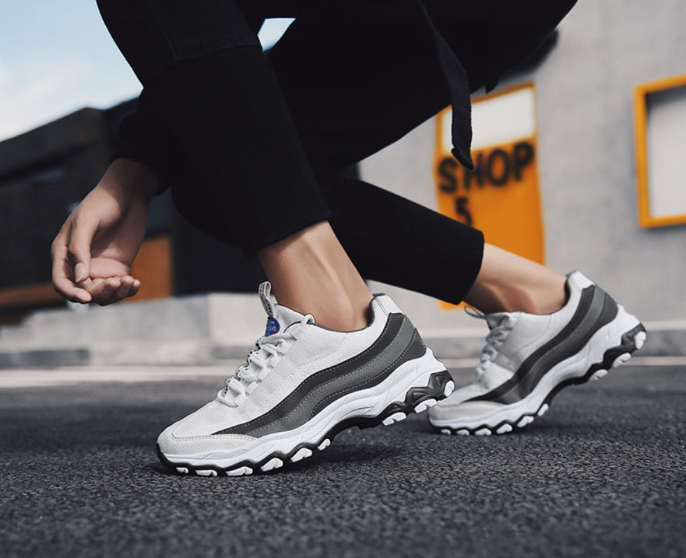 White sneakers with black gray trim and blue logo detail
