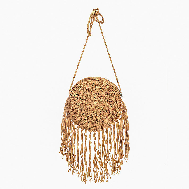 Tan round crochet crossbody bag with long fringe tassels and braided shoulder strap