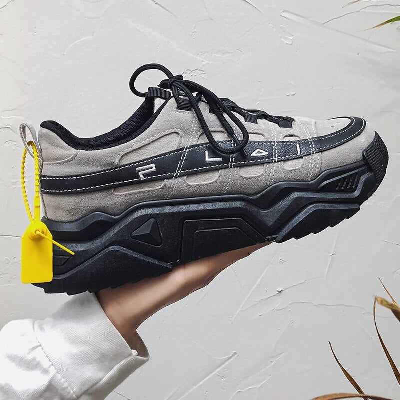 Men's chunky light grey sneakers with black laces, side details, and thick sole