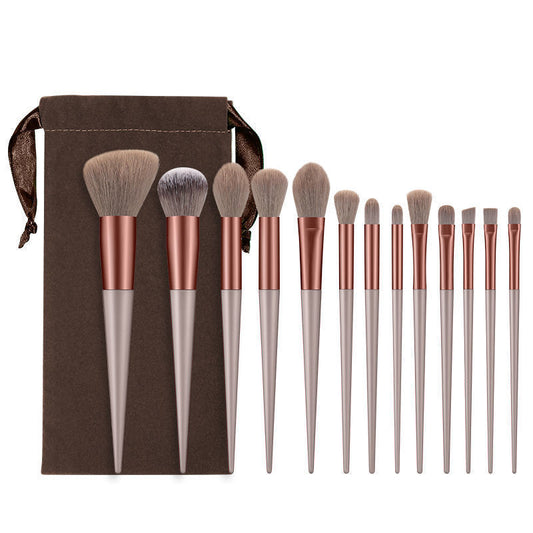Set of makeup brushes with rose gold and gray handles on a brown drawstring bag background