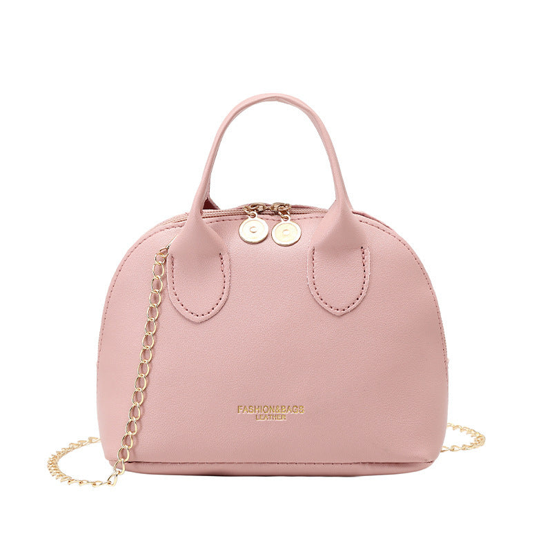 Light pink dome handbag with chain strap, curved handle tabs, gold-tone hardware
