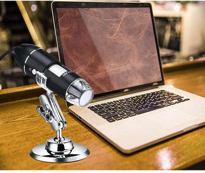 Digital microscope on a stand in front of a laptop displaying a leather texture.
