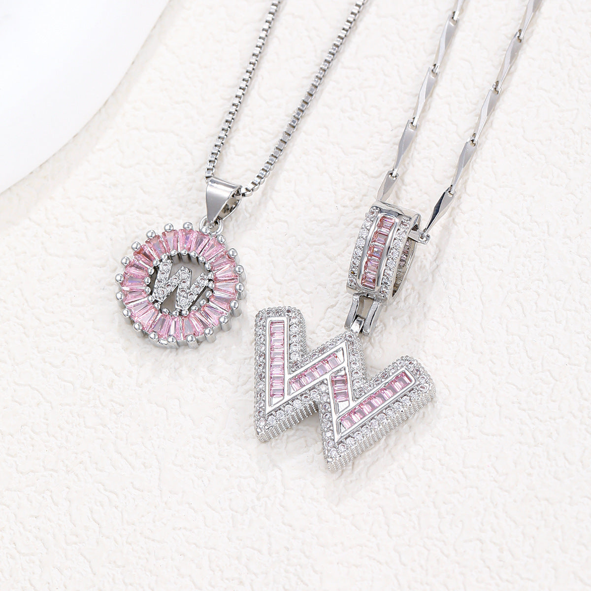 Silver-tone pendant necklace set with pink zircon rosette pendant and T-style block letter pendant.