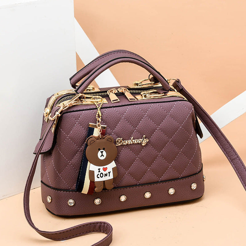 Pink quilted messenger bag with gold hardware, studded trim, bear keychain charm