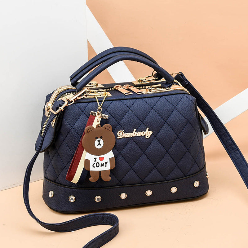 Black quilted messenger bag with gold hardware, studded trim, bear keychain charm