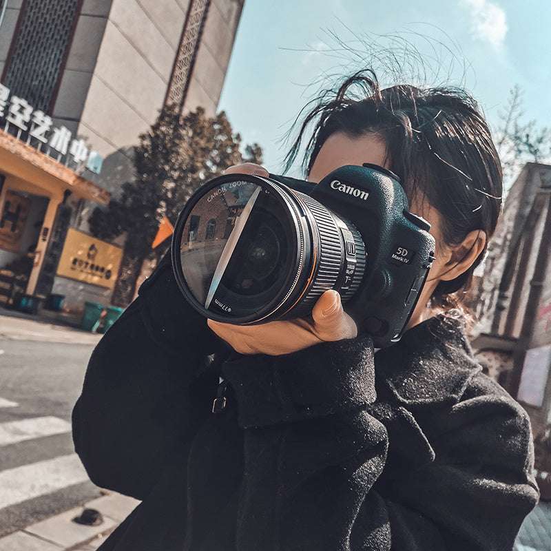 Person holding a Canon camera on a city street