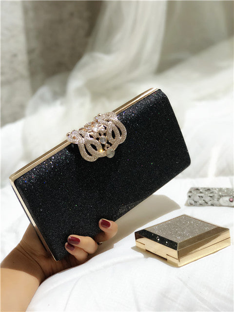 Black glitter clutch bag with gold-tone frame and crown-like rhinestone clasp