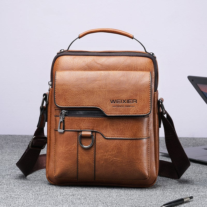 Caramel tan leather briefcase with front flap and centered ring, crossbody straps