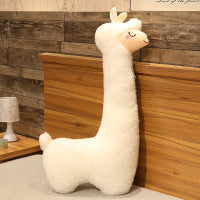 Plush llama toy against a wooden wall