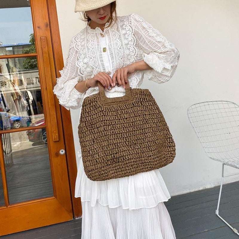 Woven straw beach handbag in dark brown with square cutout handle and open top