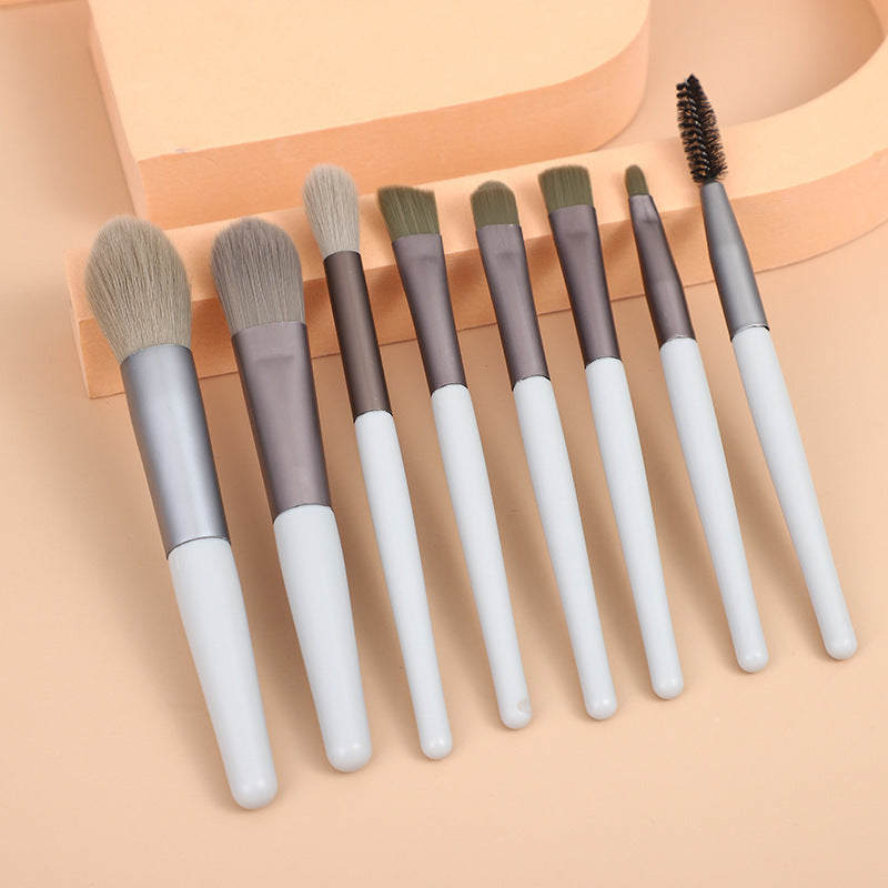 Mini makeup brush set with white handles and gray, taupe, and black brush ends