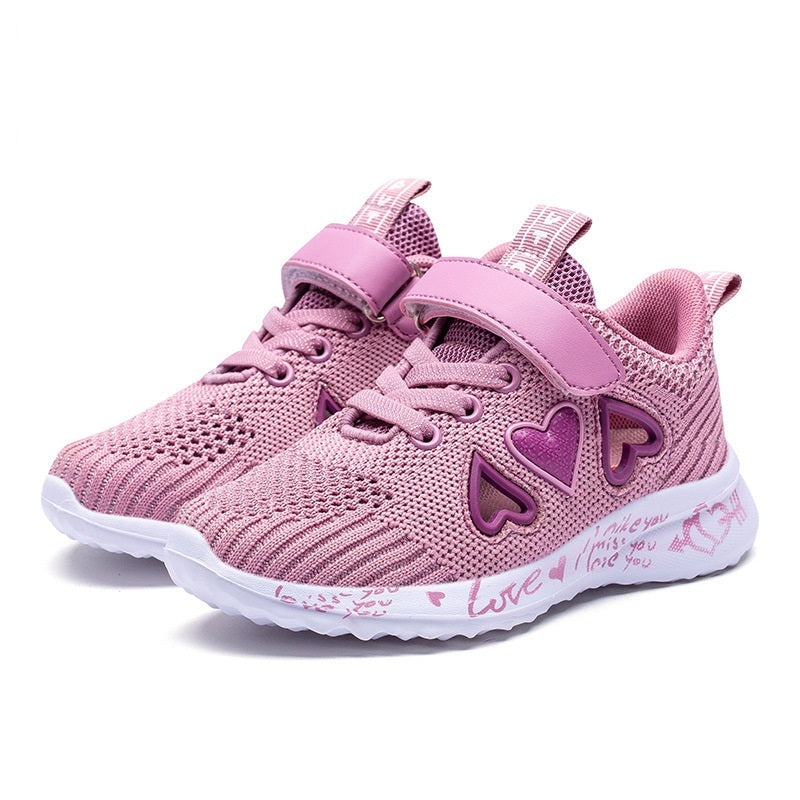 Knit mesh sports shoe with pink upper, heart decorations, double straps, and white sole.