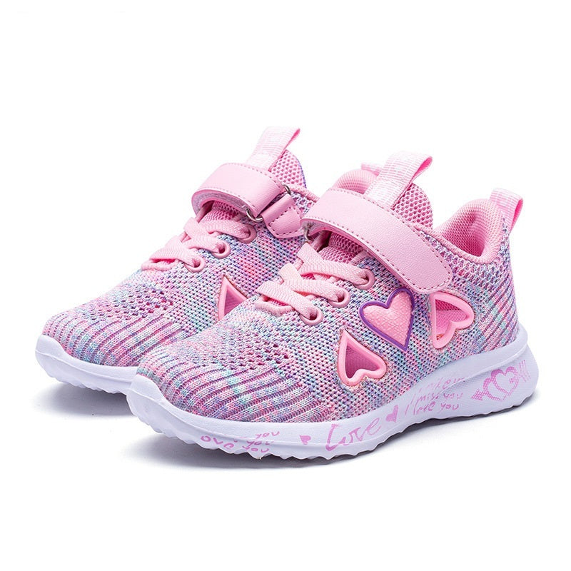 Knit mesh sports shoe with pink strap, heart charms, multicolor knit, and white sole.