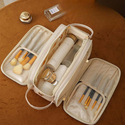 Cream cosmetic bag opened to show organizer compartments with makeup brushes and bottles