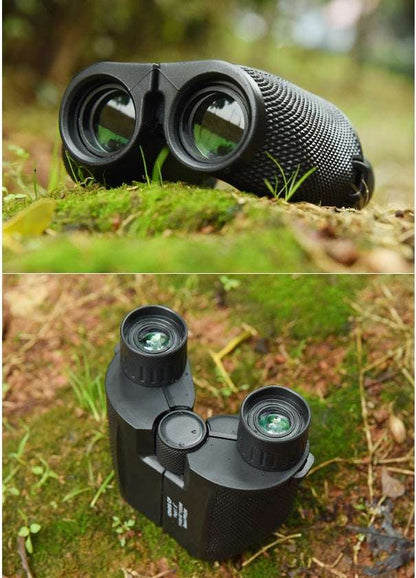 Black binoculars on a grassy surface with a blurred natural background