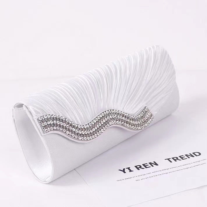 White satin clutch bag with textured ruching and rhinestone wave frame