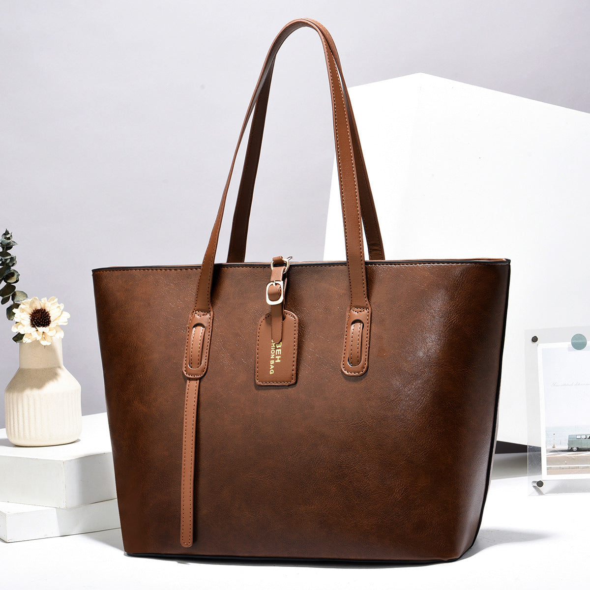 Dark brown leather handbag with top handles and front zip pocket with zipper pull tab