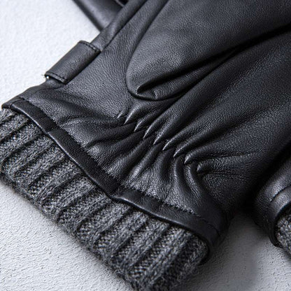 Close-up of black leather gloves with gray ribbed cuffs on a light gray background