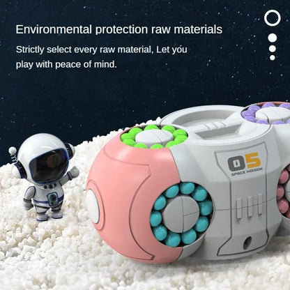 Rotating fidget cube toy with gray body, green bead ring, and pink bead ring