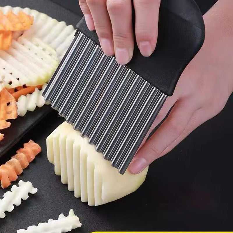 Hand-held crinkle cutter with wavy blade comb, slicing ridged vegetable pieces
