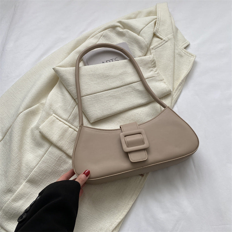 Khaki small crossbody bag with curved shape, top handle, and front buckle detail