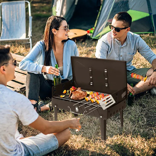 Black square charcoal grill outdoors with food cooking on the grate