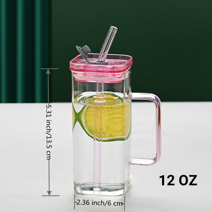 Square glass drinking cup with straw and lid, pink lid and clear body with handle.