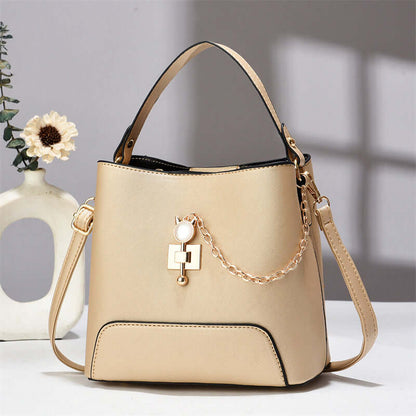 Beige PU leather bucket bag with top handle, shoulder strap, and gold chain charm