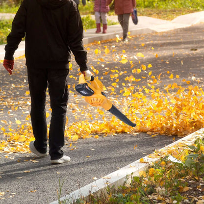Orange cordless leaf blower with black tube blowing debris from pavement