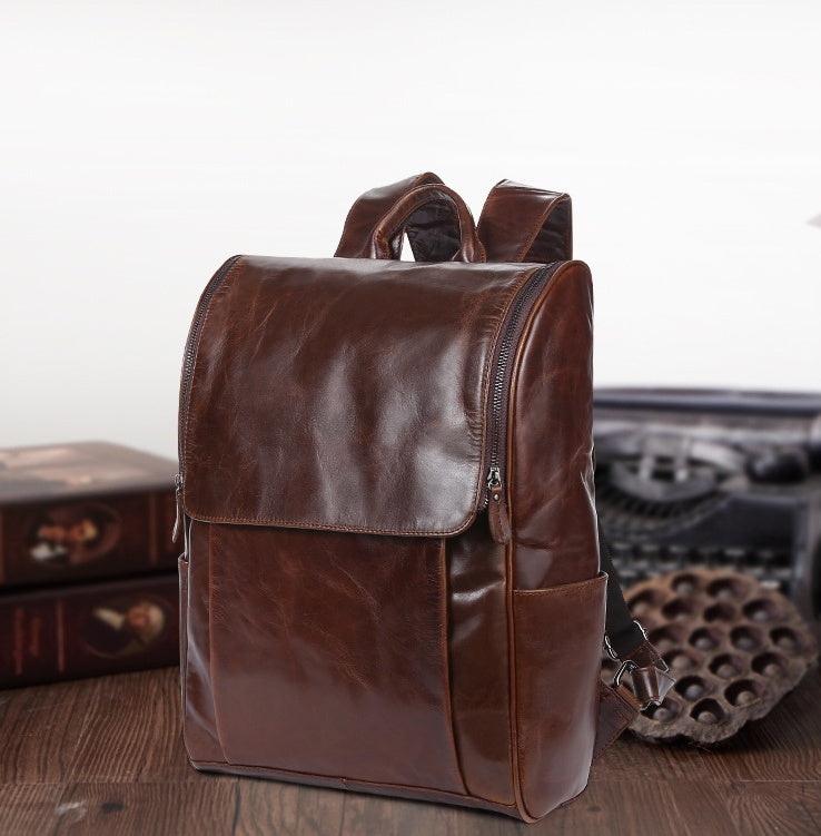 Brown leather laptop backpack with top handle, front flap pocket, and side zipper
