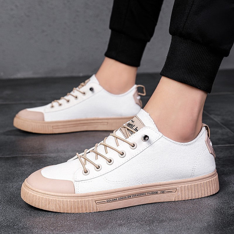 White low-top sneakers with tan lace-up and rubber sole, side label detail