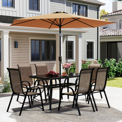 Patio dining set with brown mesh chairs around glass table under tan umbrella on concrete.
