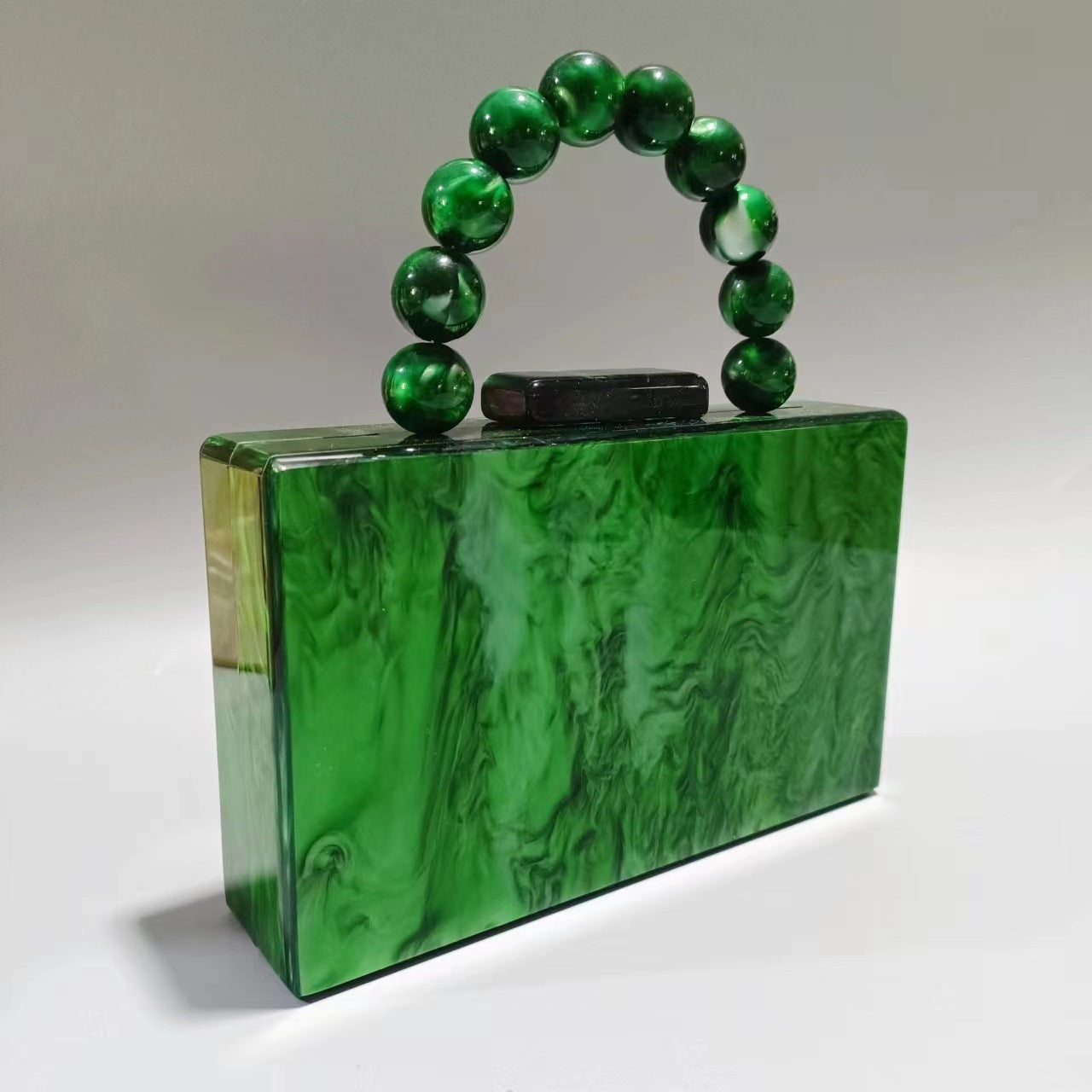 Women's acrylic evening bag with green marbled body and dark green beaded handle