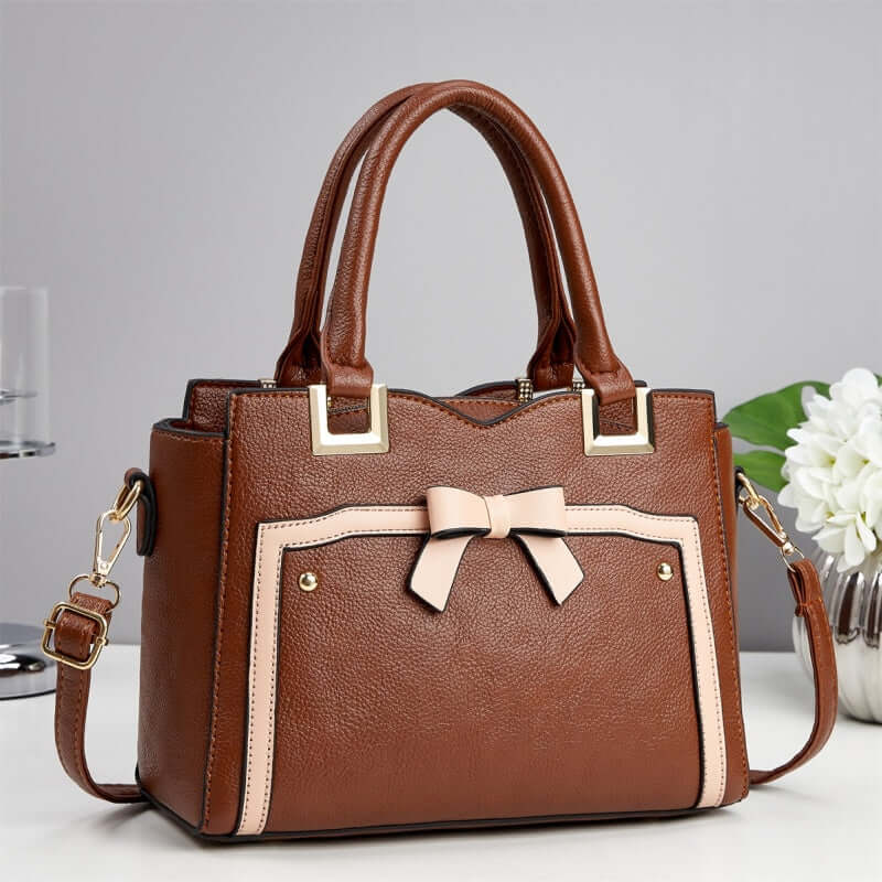Brown commuting shoulder bag with cream trim, bow front, and shoulder strap