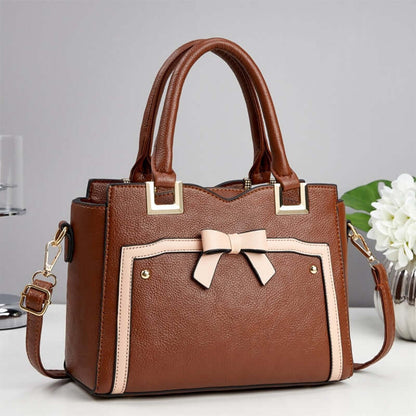 Brown commuting shoulder bag with cream trim, bow front, and shoulder strap
