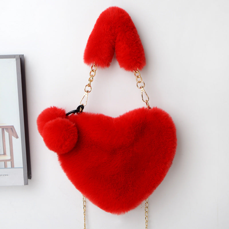 Heart-shaped plush handbag with pom-pom accents and gold chain strap, red