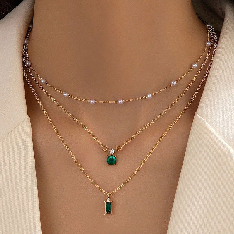 Multilayer pearl necklace with gold chain, pearl choker, and green round and bar pendants