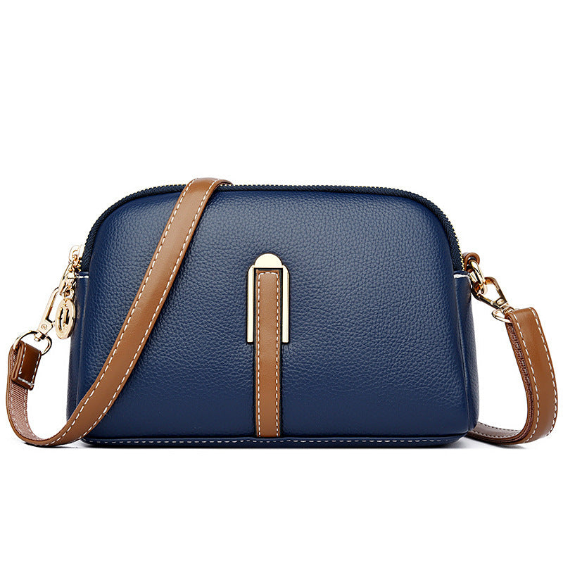 Blue textured shoulder bag with zip top and tan front strap detail
