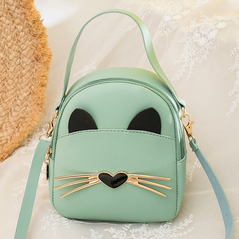 Mint green mini cat-face backpack with gold heart whiskers, top handle, and crossbody strap