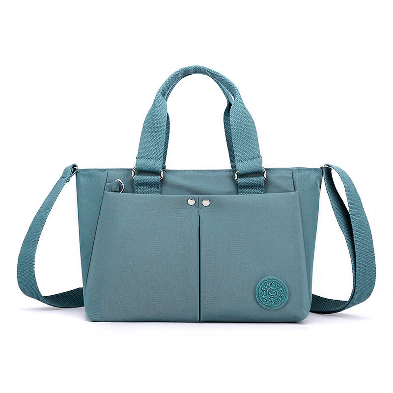 Waterproof shoulder bag in teal with front center seam and matching webbing straps